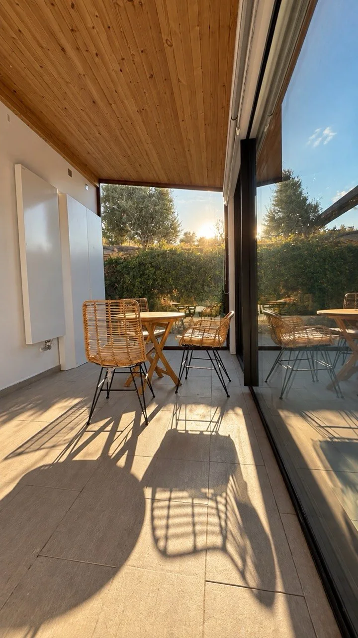 Sunlight falling across a dining table and chairs on the covered glass terrace